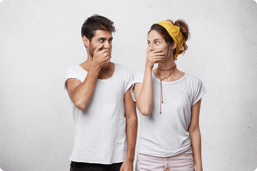 Man and woman laughing while covering mouths, explaining why like the smell of own farts