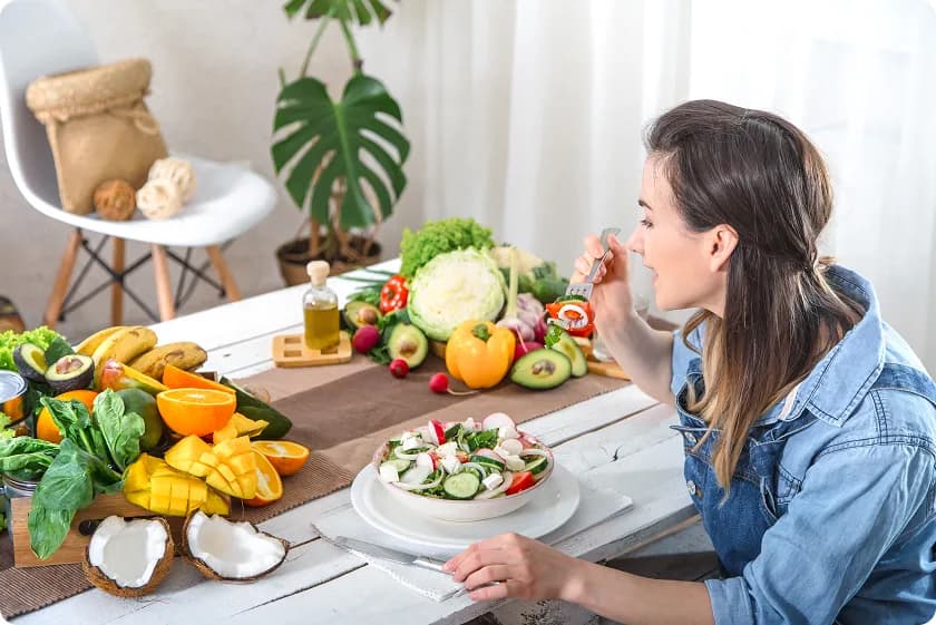 Woman eating fresh salad with fruits and vegetables demonstrating gout exercise and healthy diet