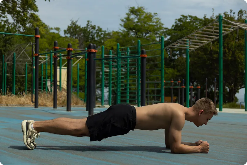 Man holding plank position outdoors to perform bodyweight-exercises and arm workouts without equipment.