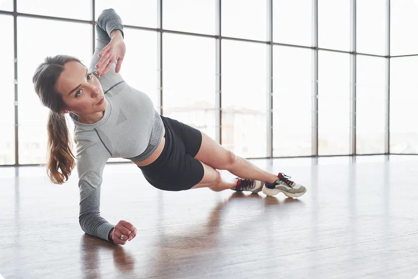 Female doing side plank to strengthen core and back exercises no equipment.