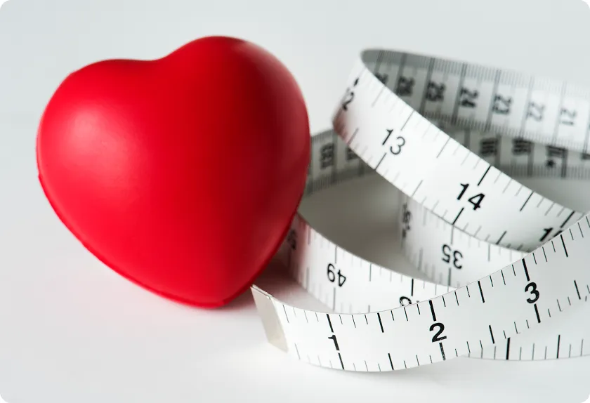 Measuring tape around a heart model comparing a healthy heart vs unhealthy habits.
