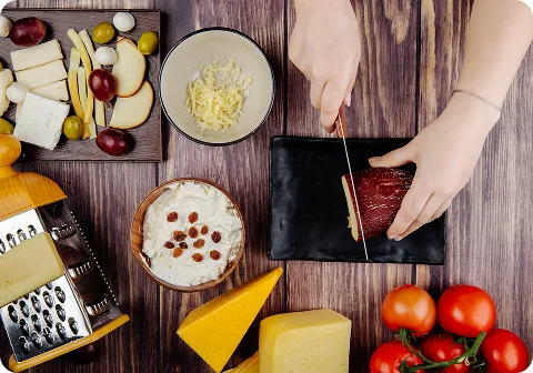 Hands slicing meat with cheese and the keto diet ingredients