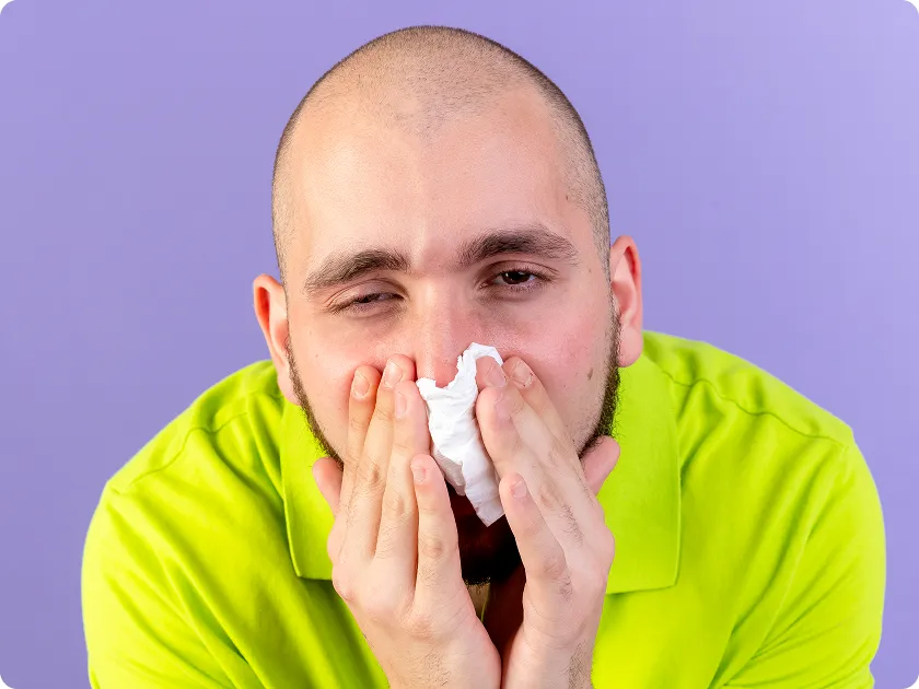 Man wiping his congested nose with a tissue showing signs of nasal polyps.